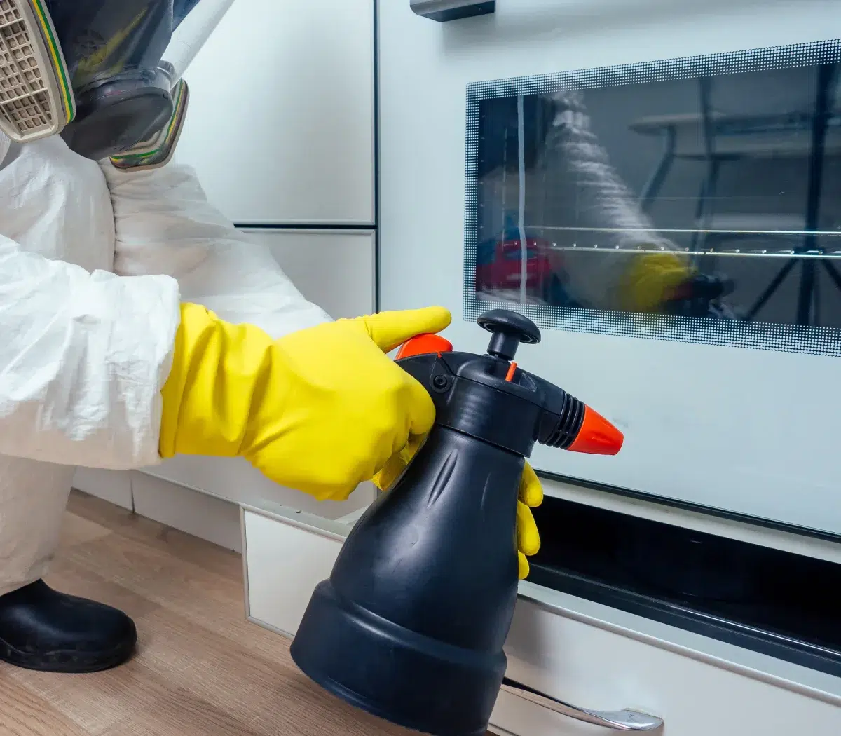 Personne nettoyant un four avec pulvérisateur